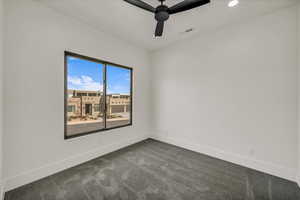 Unfurnished room with ceiling fan and dark colored carpet