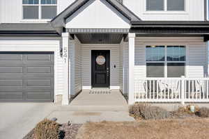 View of exterior entry featuring a garage and covered porch