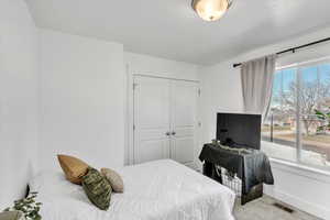 Carpeted bedroom with multiple windows and a closet