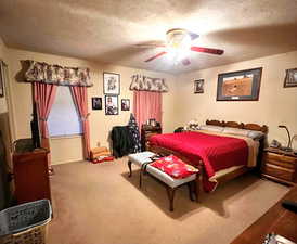 Bedroom with ceiling fan, a textured ceiling, and carpet