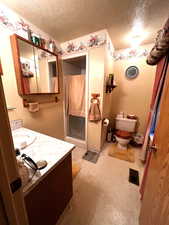 Bathroom with vanity, toilet, a textured ceiling, and walk in shower