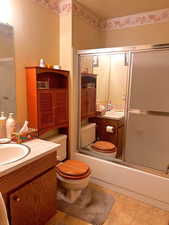 Full bathroom featuring enclosed tub / shower combo, vanity, toilet, and a textured ceiling