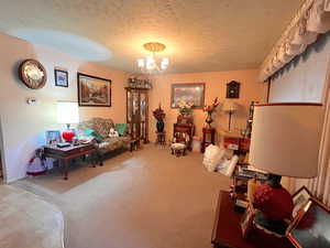 Sitting room with carpet floors, a notable chandelier, and a textured ceiling