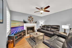 Living room featuring hardwood / wood-style flooring, ceiling fan, and a tiled fireplace