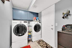 Washroom with cabinets, washer and dryer, and light tile patterned floors