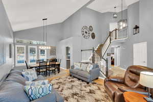 Living room with wood-type flooring, high vaulted ceiling, and a notable chandelier