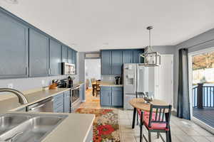 Kitchen with stainless steel appliances, hanging light fixtures, sink, and light tile patterned floors