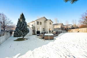 Snow covered house featuring a hot tub and a deck