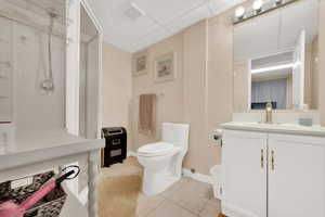 Bathroom featuring a paneled ceiling, vanity, toilet, and tile patterned flooring