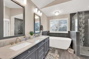 Bathroom featuring lofted ceiling, plus walk in shower, hardwood / wood-style floors, and vanity