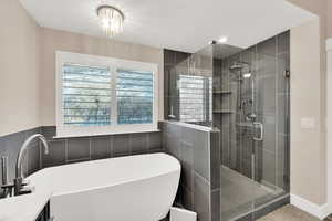 Bathroom with vanity, independent shower and bath, a textured ceiling, and tile walls