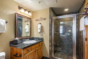 Bathroom with vanity, toilet, a shower with shower door, and a textured ceiling