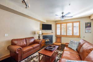 Living room featuring ceiling fan, track lighting, and a textured ceiling