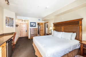 Carpeted bedroom with refrigerator