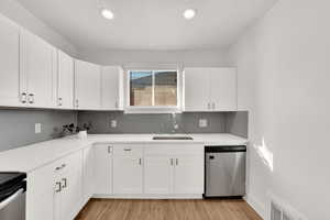 Kitchen featuring sink, light hardwood / wood-style flooring, stainless steel appliances, tasteful backsplash, and white cabinets