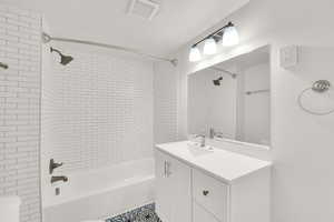 Bathroom with tiled shower / bath, vanity, and a textured ceiling