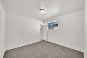 Empty room with a textured ceiling and dark colored carpet