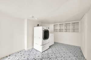 Laundry room featuring built in shelves, washer and clothes dryer, and a textured ceiling