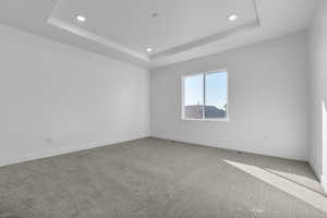 Empty room featuring carpet and a tray ceiling