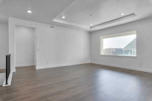 Unfurnished room with a tray ceiling and dark hardwood / wood-style floors