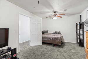 Carpeted bedroom featuring a textured ceiling and ceiling fan