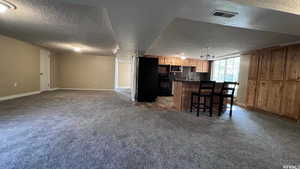 Kitchen with carpet floors, black appliances, and a breakfast bar