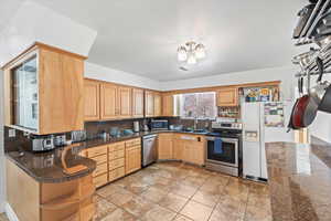 Kitchen featuring sink, backsplash, stainless steel appliances, light brown cabinetry, and kitchen peninsula