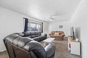 Living room featuring ceiling fan and carpet