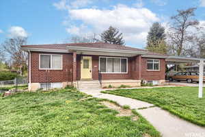 Single story home with a front lawn and a carport