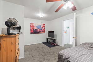 Carpeted bedroom featuring ceiling fan and a textured ceiling