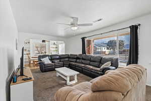 Carpeted living room with a healthy amount of sunlight and ceiling fan