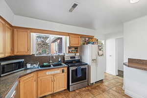 Kitchen featuring tasteful backsplash, appliances with stainless steel finishes, sink, and light tile patterned floors