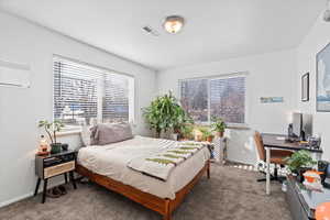 Bedroom featuring carpet floors and an AC wall unit