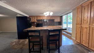 Kitchen featuring a breakfast bar, an inviting chandelier, a center island, carpet, and black appliances