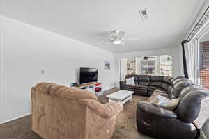 Living room featuring ceiling fan and dark carpet