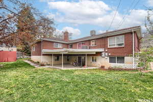 Rear view of property featuring a lawn, central AC unit, and a patio area