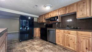 Kitchen featuring sink, decorative backsplash, black appliances, and a textured ceiling