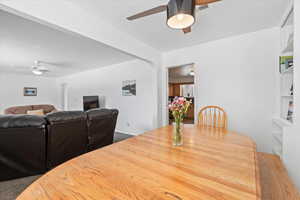 Carpeted dining space with ceiling fan and built in features