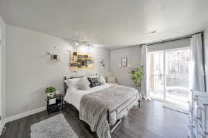 Bedroom with dark hardwood / wood-style flooring, access to exterior, and track lighting