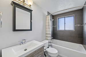 Full bathroom featuring vanity, shower / bath combination with curtain, and toilet