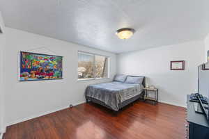 Bedroom with dark hardwood / wood-style floors and a textured ceiling