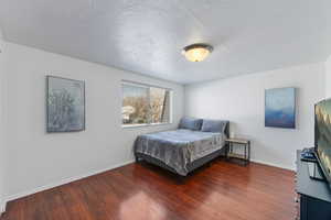 Bedroom featuring a textured ceiling and dark hardwood / wood-style flooring