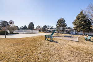 View of play area featuring basketball hoop and a lawn