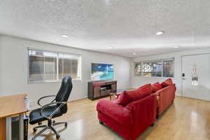 Living room with a textured ceiling and light hardwood / wood-style floors