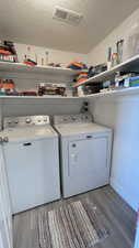 Clothes washing area featuring independent washer and dryer, hardwood / wood-style floors, and a textured ceiling