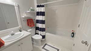 Full bathroom with tile patterned flooring, shower / bath combo, vanity, and toilet