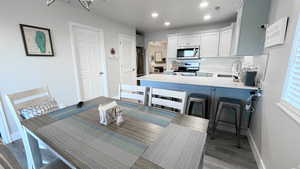 Kitchen featuring appliances with stainless steel finishes, tasteful backsplash, sink, white cabinets, and hardwood / wood-style flooring