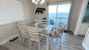 Dining area featuring a water view, an inviting chandelier, and light hardwood / wood-style floors