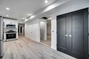 Kitchen featuring stainless steel appliances, white cabinets, and light hardwood / wood-style floors