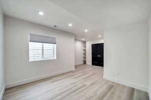 Empty room with built in shelves and light hardwood / wood-style floors